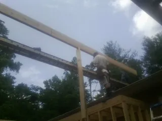 Carpenter setting a ridge beam over a new addition frame — Ice Dam Removal by Roofing Brothers in Nettleton
