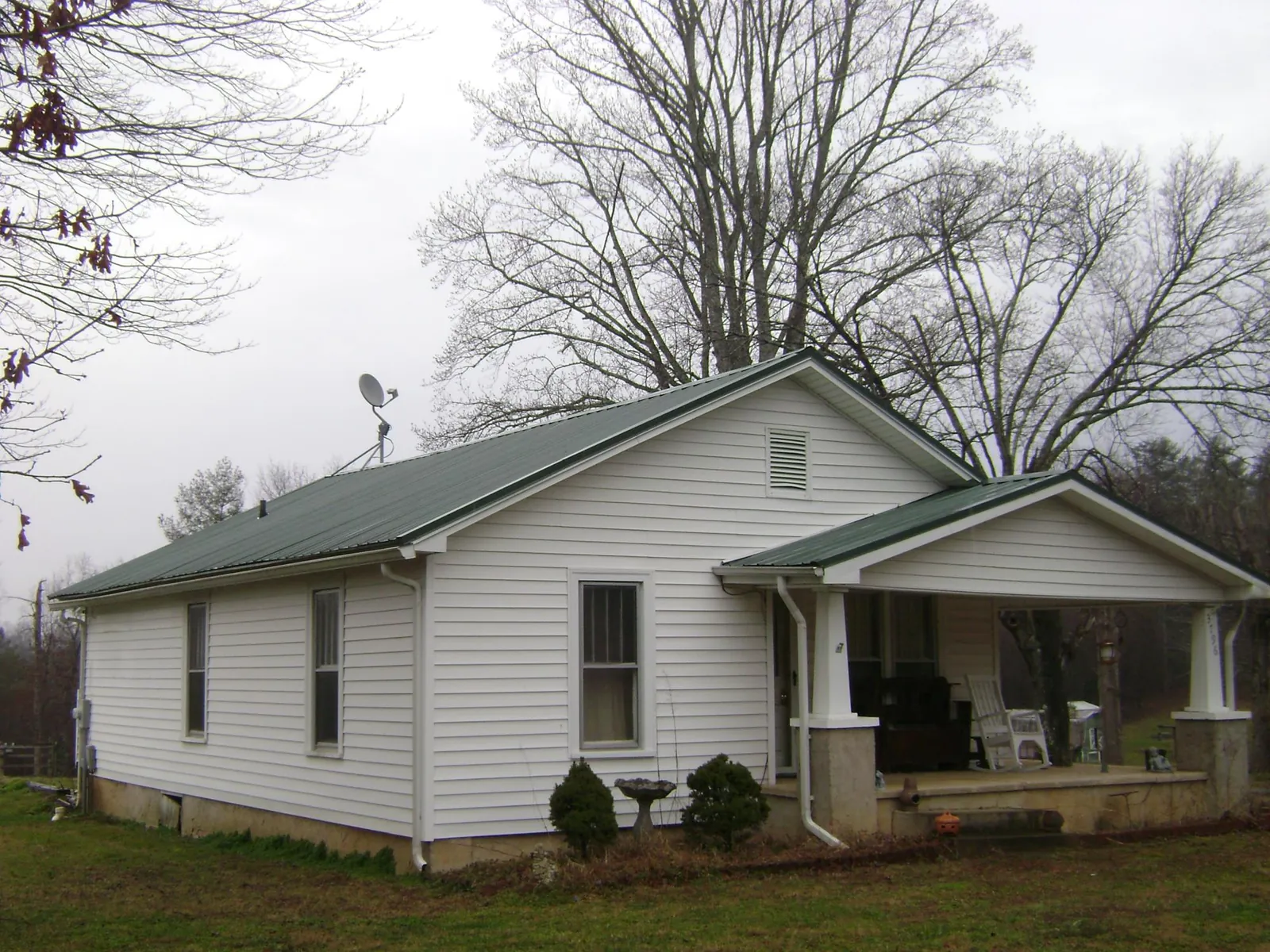 Green metal roof on a white bungalow with a side porch in Nettleton