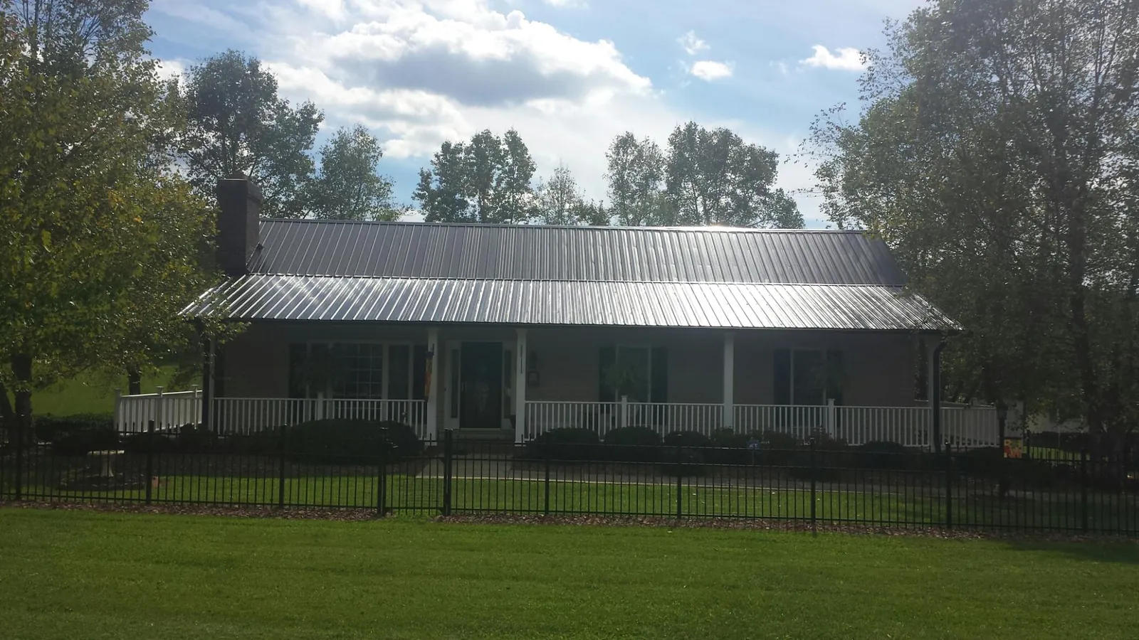 Gray metal roof on a brick ranch with a full width front porch — Gutter Guard Installation work by our crew in Nettleton