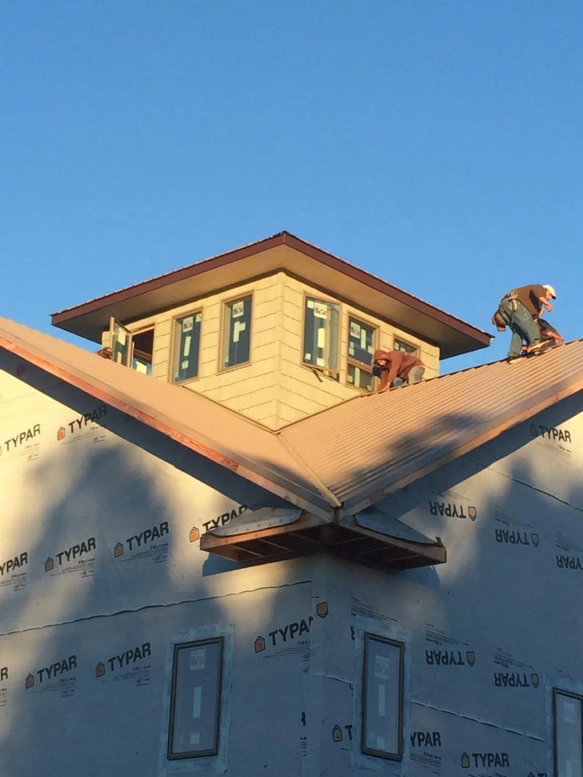 Roofers working around a rooftop cupola on a new metal roof at sunset — Roof Waterproofing in Nettleton by Roofing Brothers